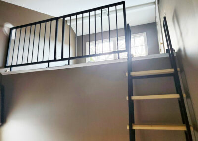 Loft Living Space With Black Steel Railing and Loft Ladder